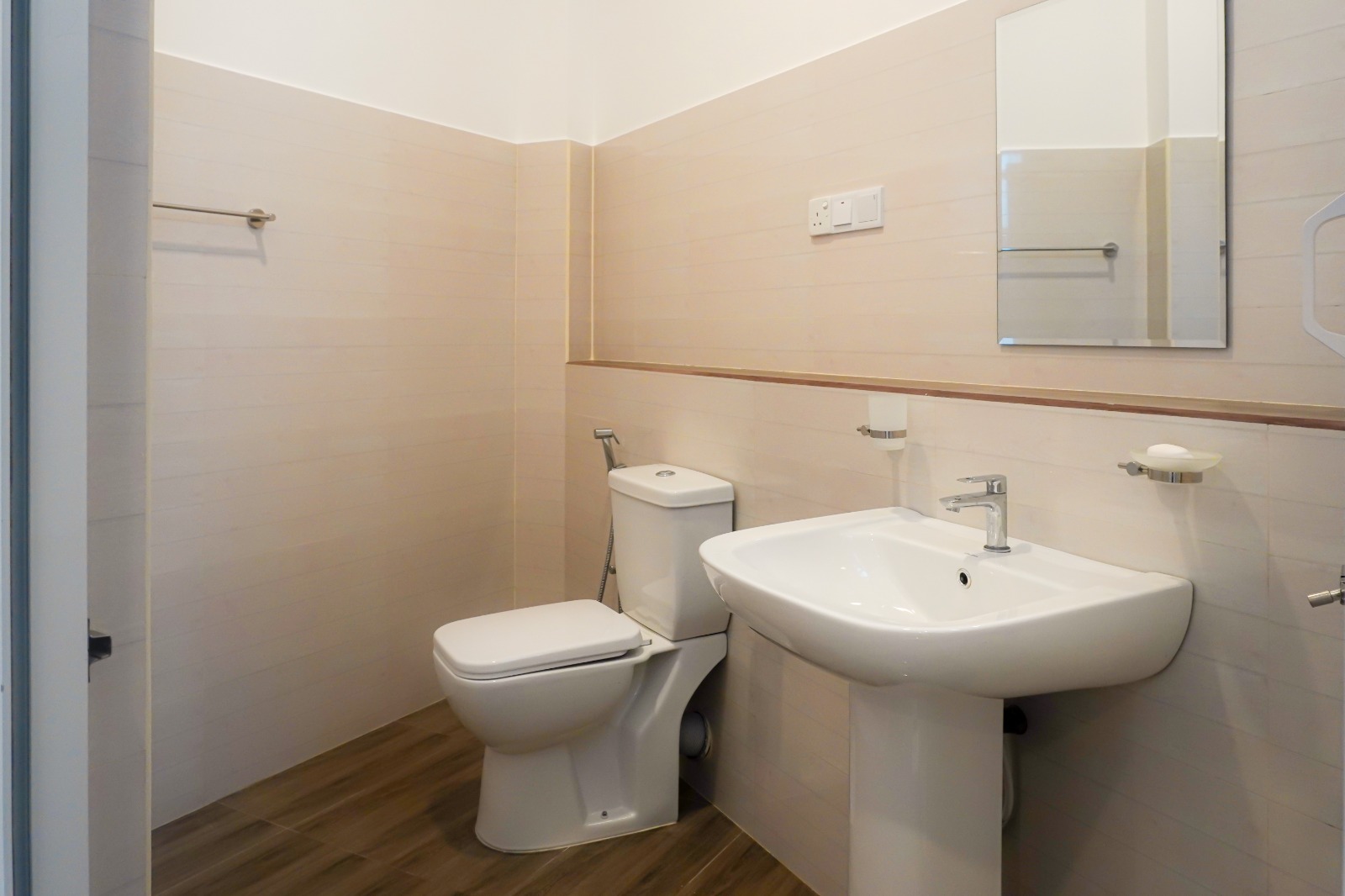 Private bathroom with a pedestal washbasin, mirror, toilet and wood-effect floor tiles
