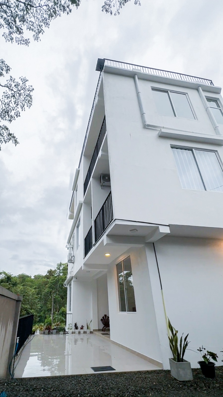 Romara Living's white multi-storey building with balconies and a rooftop railing, framed by trees