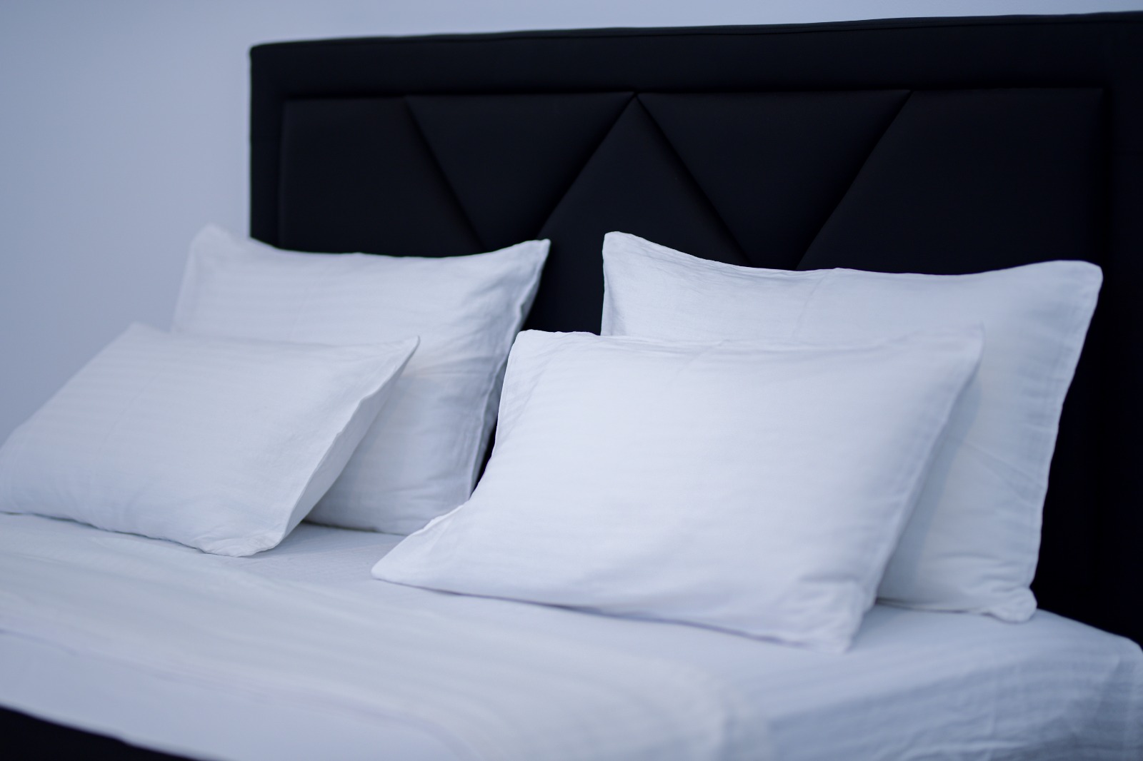 Crisp white pillows and linen against a dark upholstered headboard