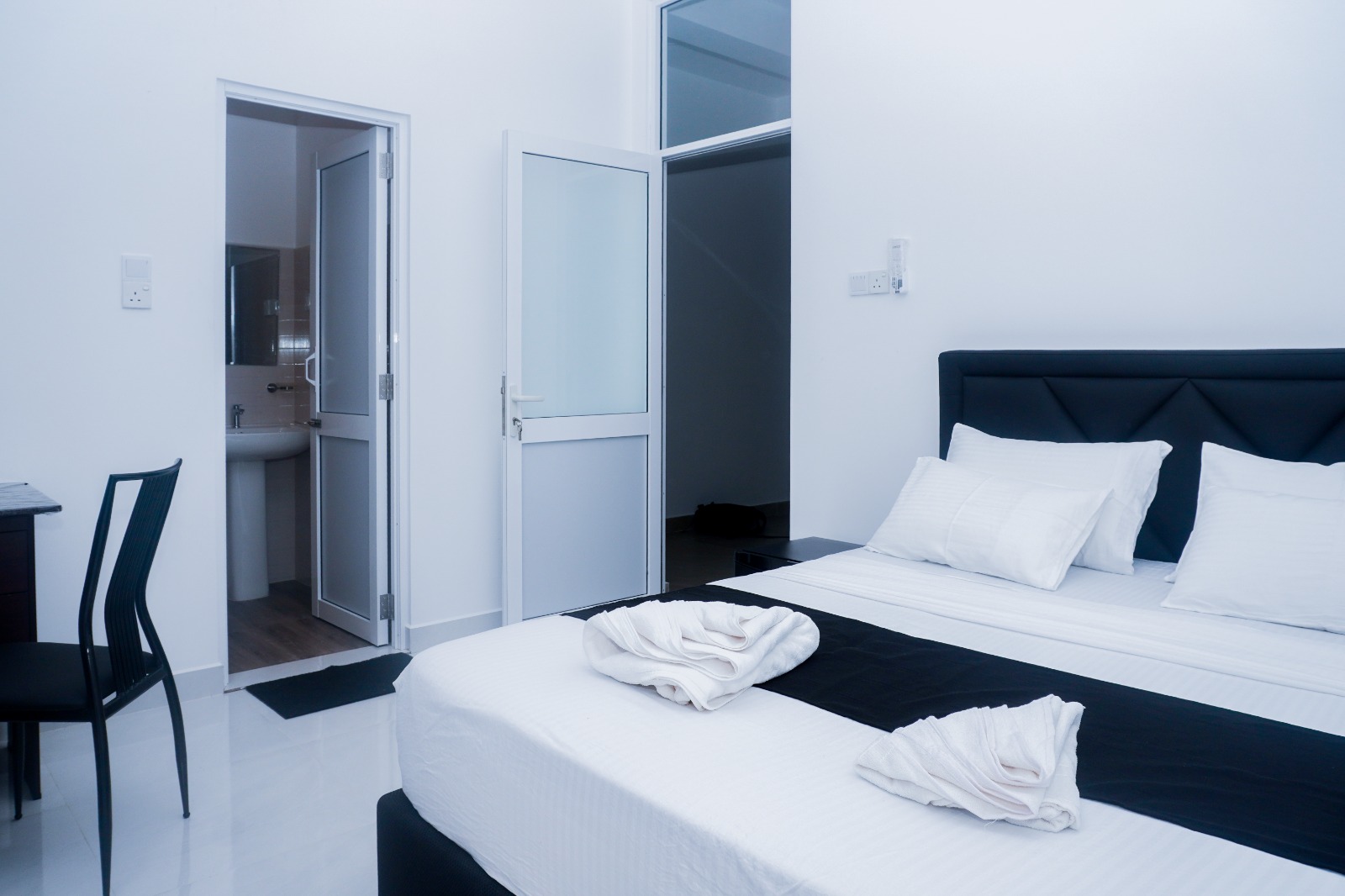 Double bed with folded towels and the door to the private en-suite bathroom
