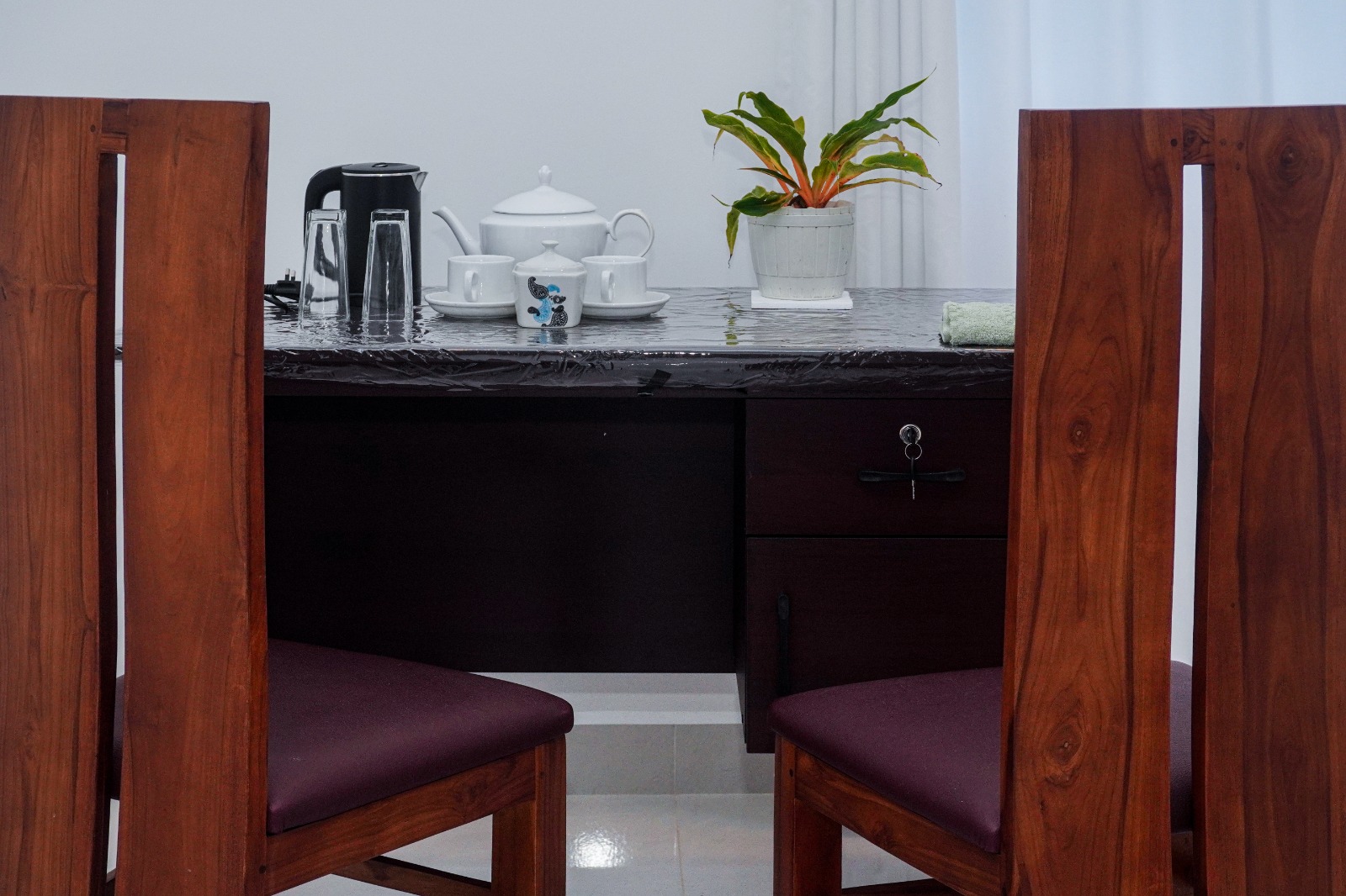 Writing desk with a tea tray between two wooden chairs in a guest room